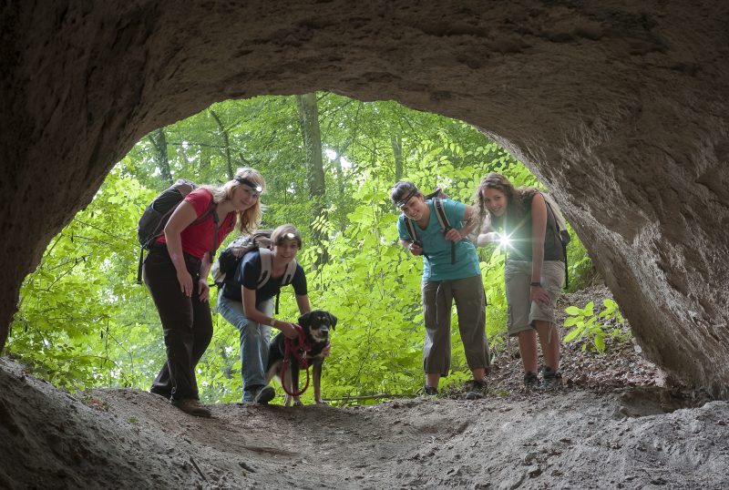 Jugendliche Wanderer blicken in die Höhle
